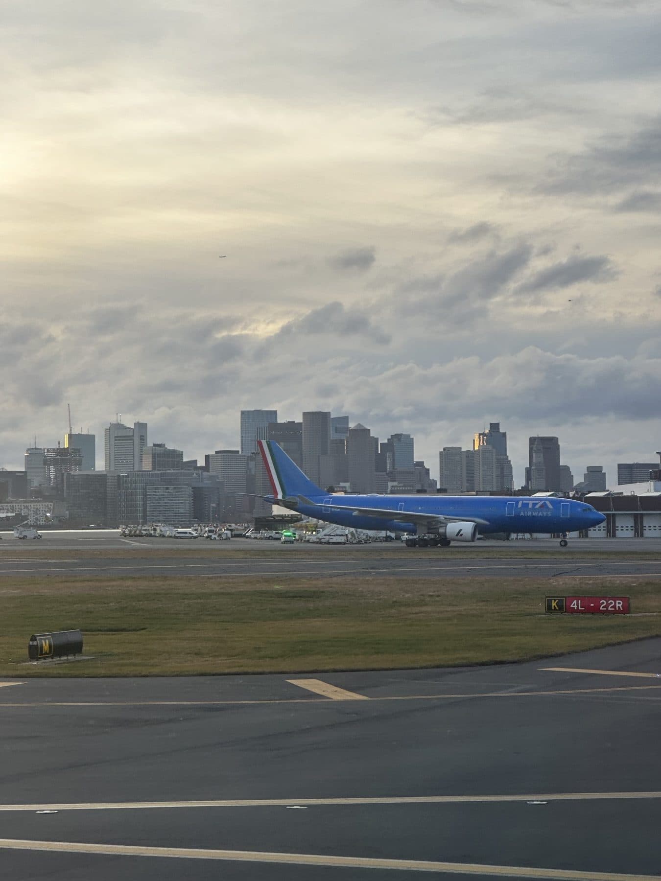 An ITA Airways Airbus A330 taxiing at Boston Logan with the Boston skyline behind it